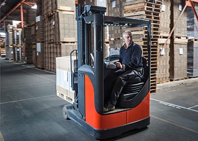 Instructor demonstrating reach truck manoeuvring in warehouse aisle