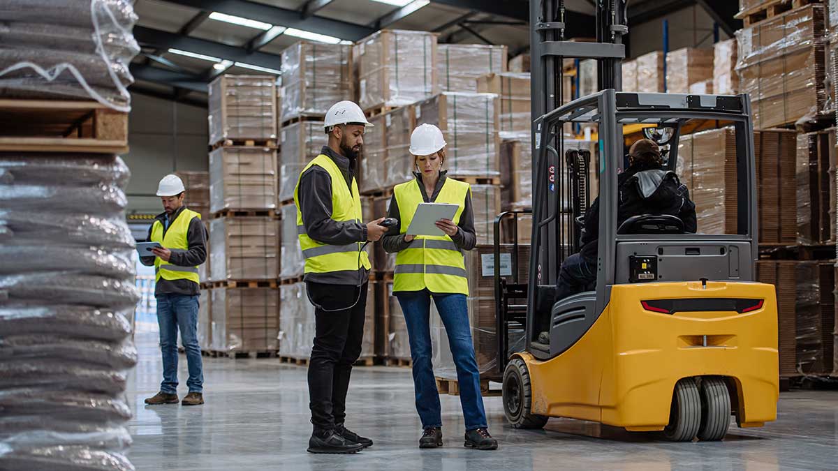 Supervisor observing forklift operations and workplace safety procedures in a warehouse.